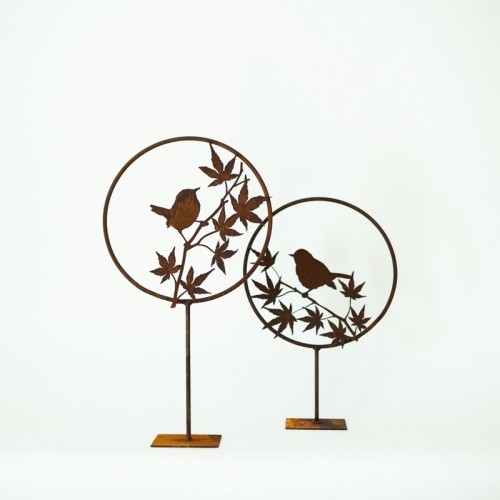 Uccellino in metallo arrugginito su ramo con piedistallo